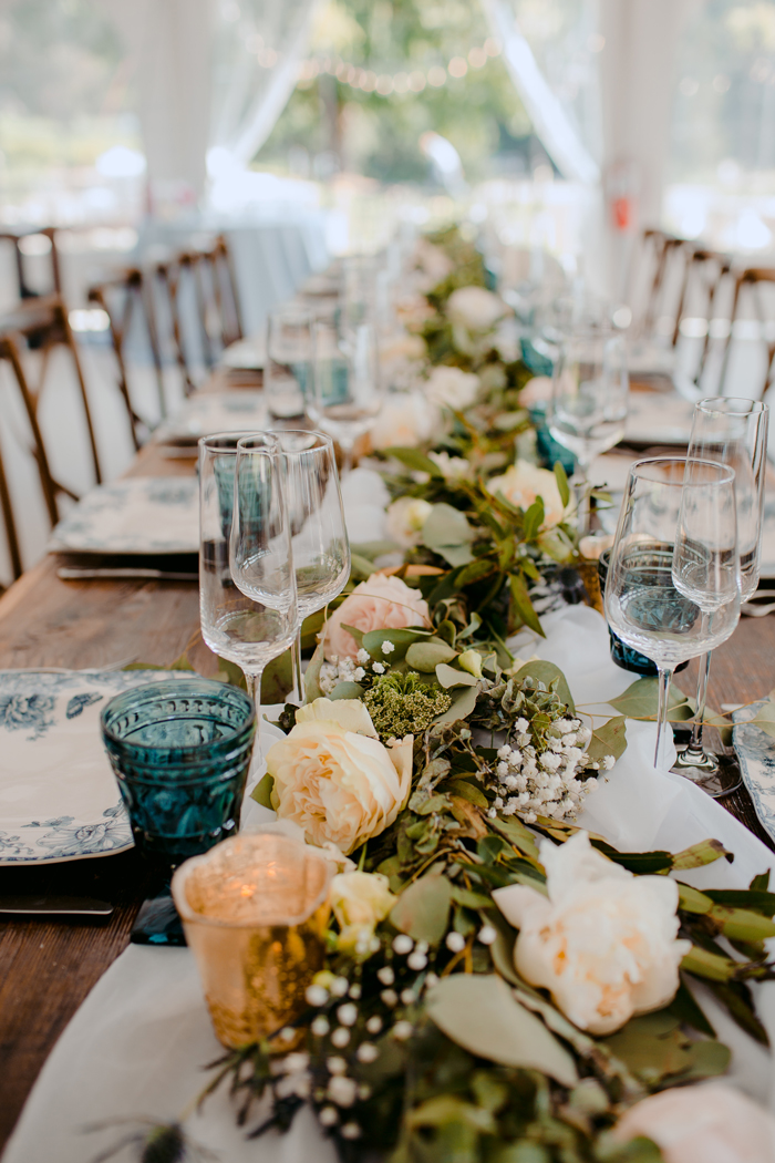 A long wooden table with flowers and greenery.